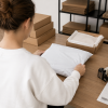 Achteraanzicht van een persoon die een witte LDPE verzendzak inpakt aan een werktafel, ter illustratie van het veilig verpakken en verzenden van kleding of zachte producten