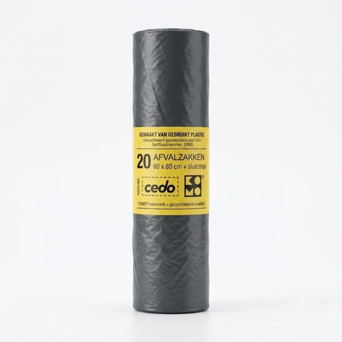 Een studiofoto van een rechtopstaande rol grijze Cedo afvalzakken tegen een egale, helderwitte achtergrond. De rol is in het midden voorzien van een brede, gele wikkel met zwarte tekst en logo's, waarop te lezen staat: