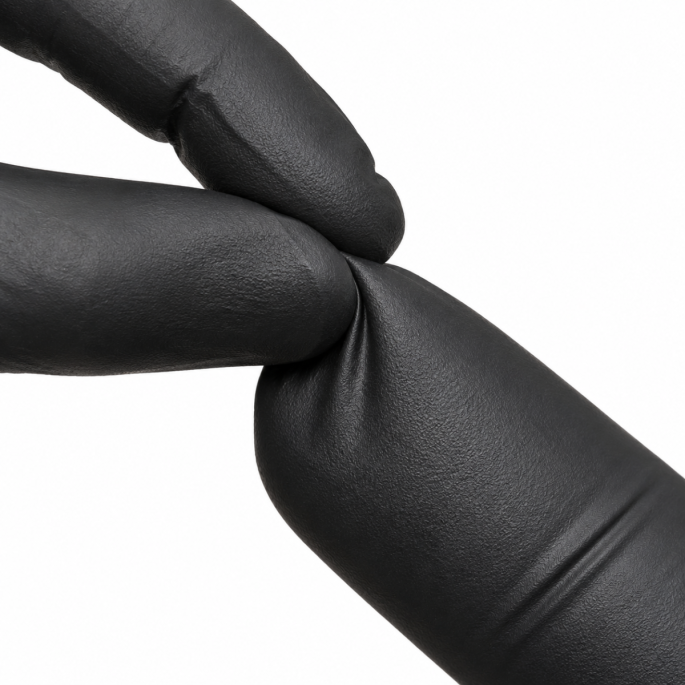 Close-up van een zwarte nitrilhandschoen waarbij twee gehandschoende vingers het materiaal stevig samenknijpen, waardoor de flexibiliteit, elasticiteit en textuur van de handschoen duidelijk zichtbaar zijn tegen een witte achtergrond.