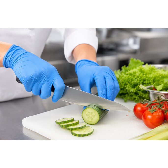 Medewerker draagt blauwe disposable nitrilhandschoenen tijdens het snijden van een komkommer op een snijplank in een professionele voedselbereidingsomgeving. De handschoenen sluiten nauw aan op de handen en bieden optimale grip, flexibiliteit en hygiëne t