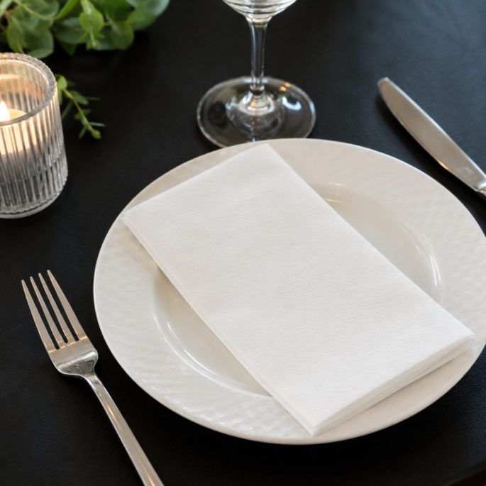 Hoogwitte 1-laags servet 1/4 vouw in gebruik op een gedekte tafel, geschikt voor horeca, restaurants, catering en professionele tafelpresentatie.