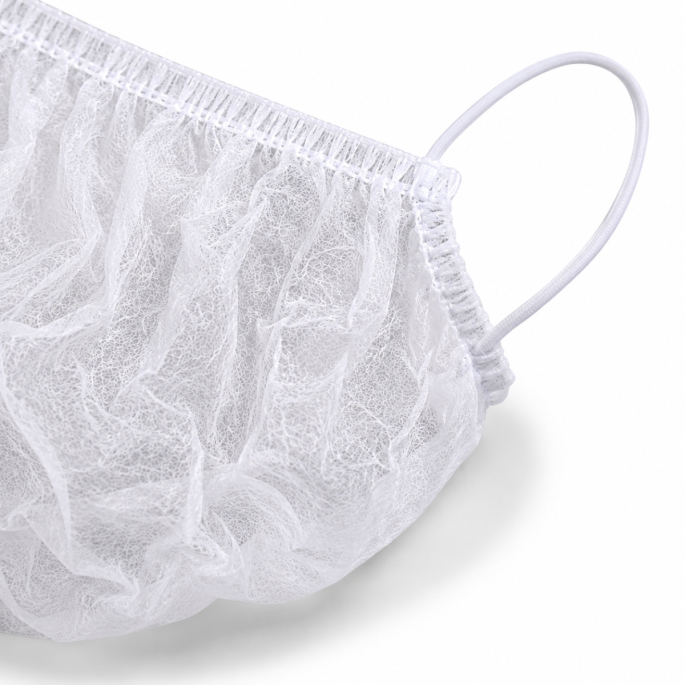Close-up van een witte disposable baardcover met focus op de elastische oorlus, geplooide afwerking en fijne non-woven vezelstructuur. De afbeelding toont de hoogwaardige afwerking van het ademende materiaal en de stevige bevestiging van de elastische lus